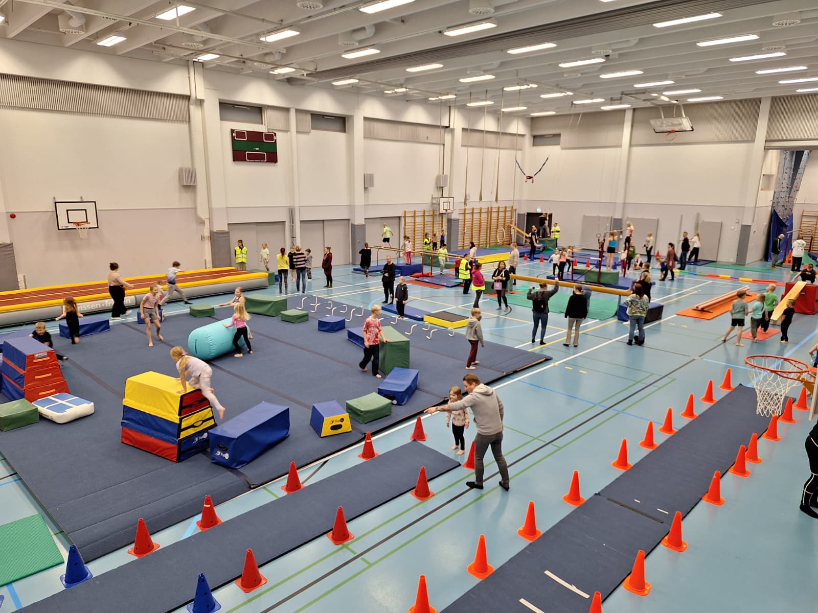 Liikuntasali yläkulmasta kuvattuna, jossa ihmisiä eri toiminnoissa.