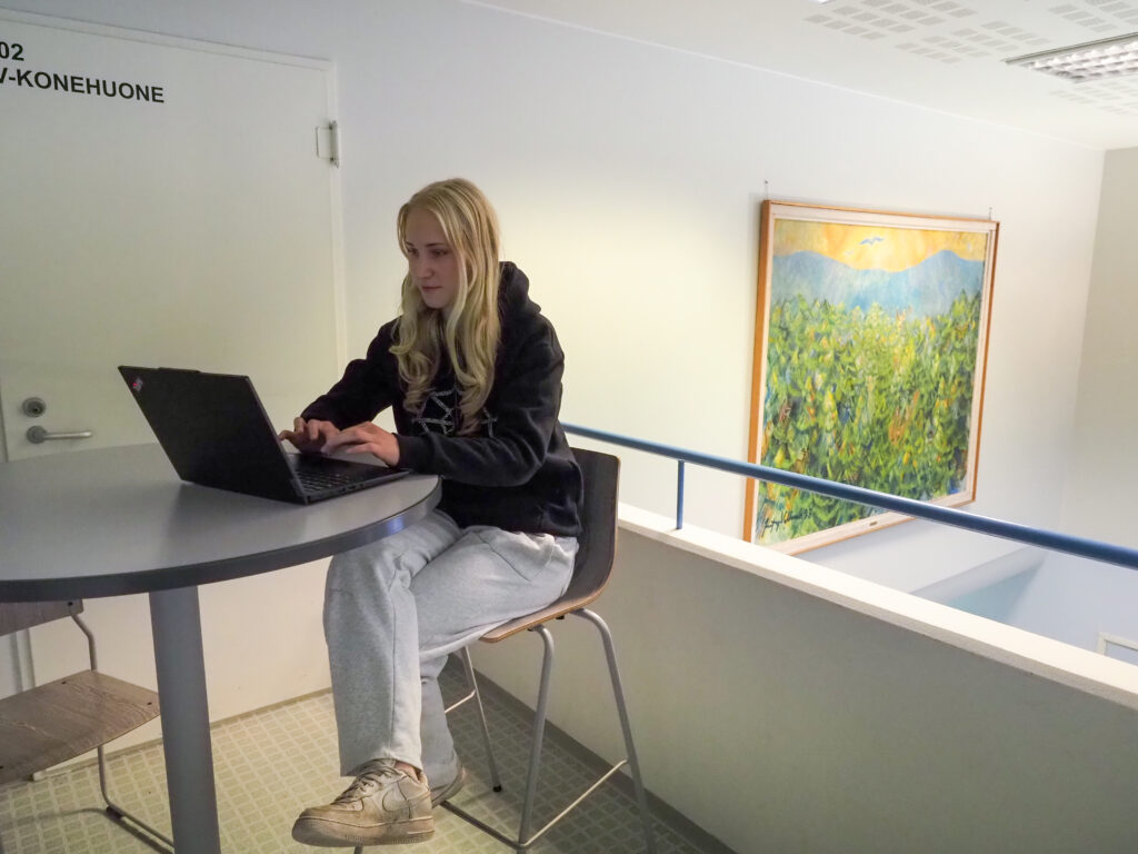 Nuori nainen istuu tietokoneen äärellä.