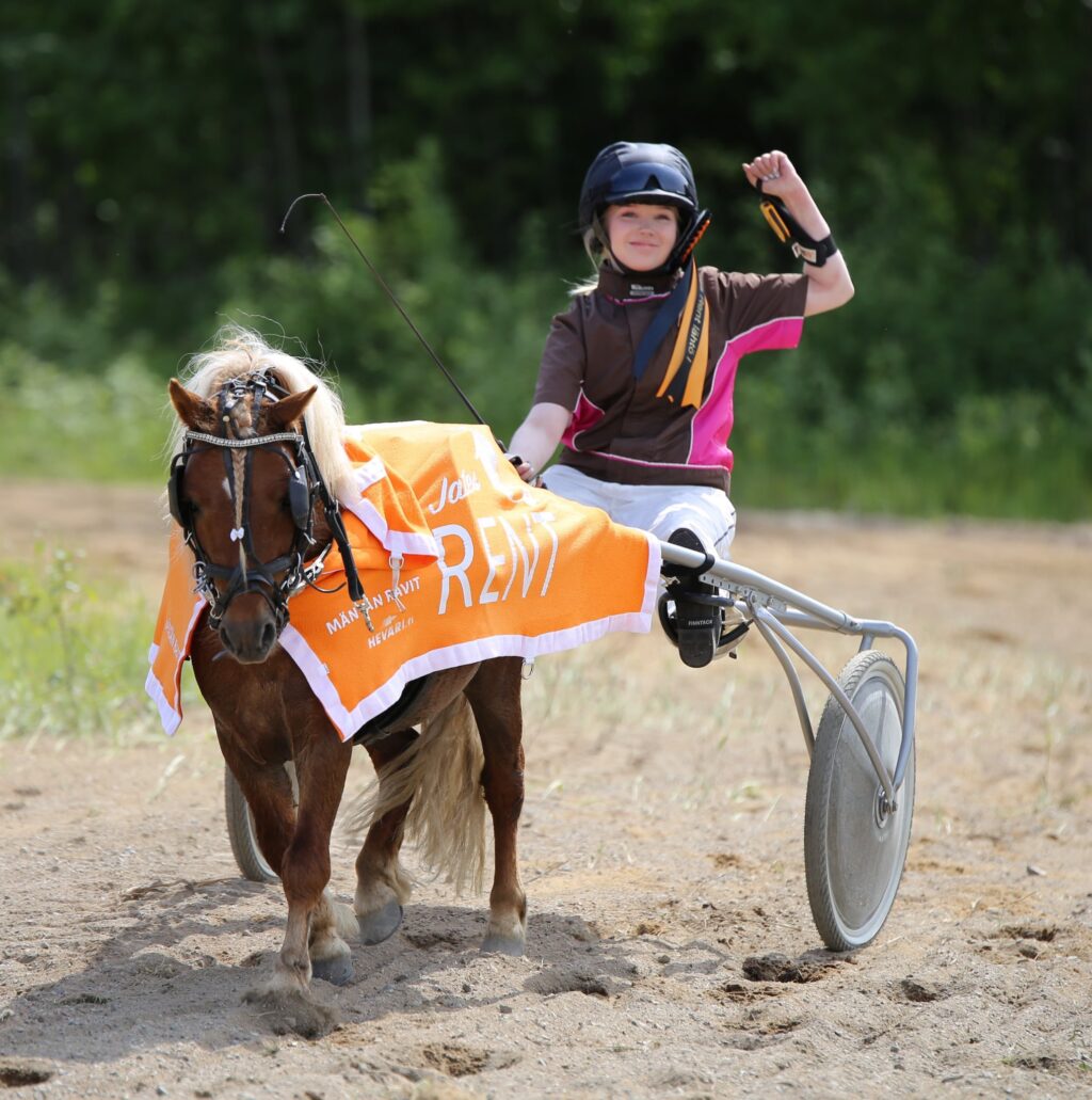 Nuori nainen ohjastamassa ponia poniraveissa, voittajan tuuletus.