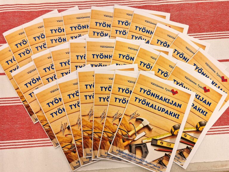 Esitteitä levitettynä pöydälle. Esitteen kannessa kuvia työkaluista ja teksti Työnhakijan työkalupakki.