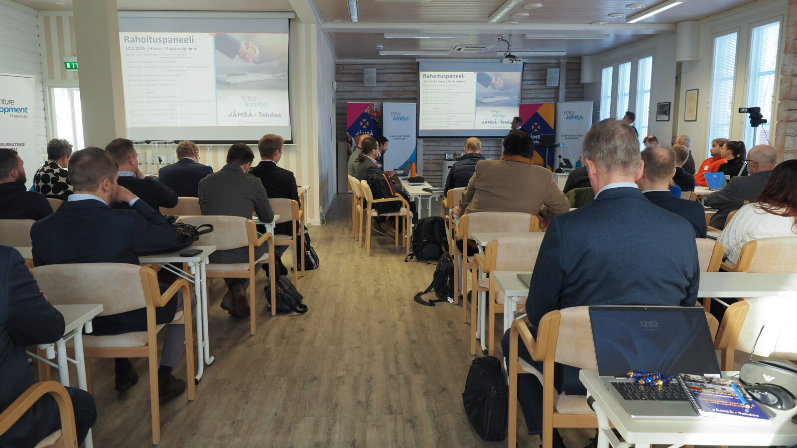 Ihmisiä istumassa pöytien äärellä.