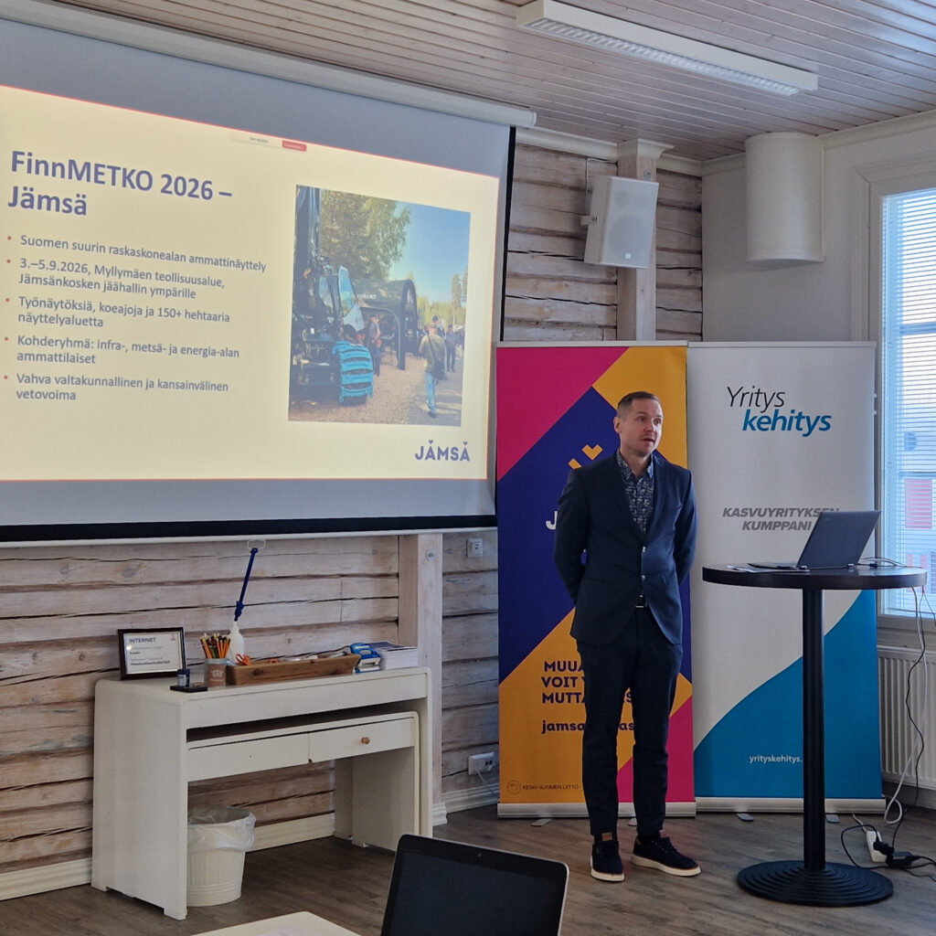 Ihminen seisomassa suuren näytön vierellä.