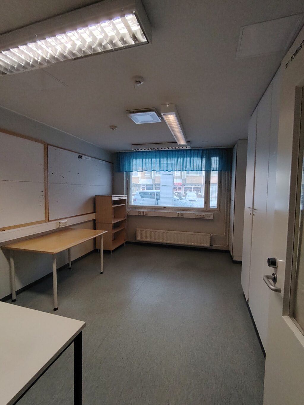 Tyhjä huone, jossa pöytä ja lipasto, ikkuna.