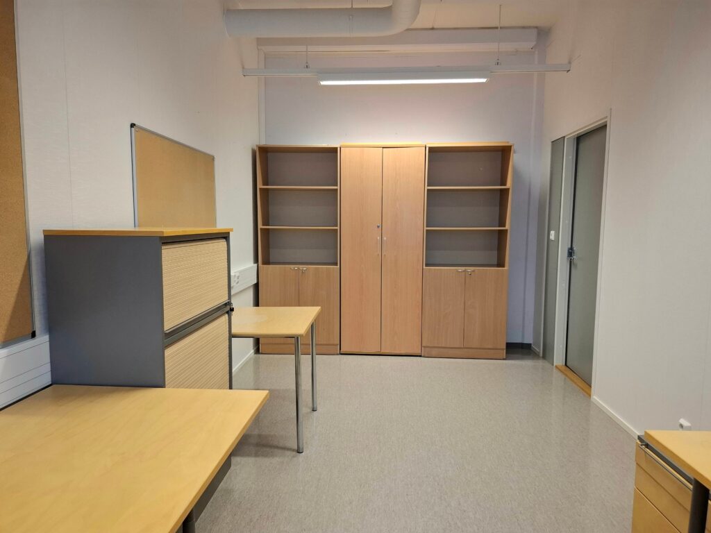 Huone, jossa pöytiä ja kaapistoja, toimistotila.