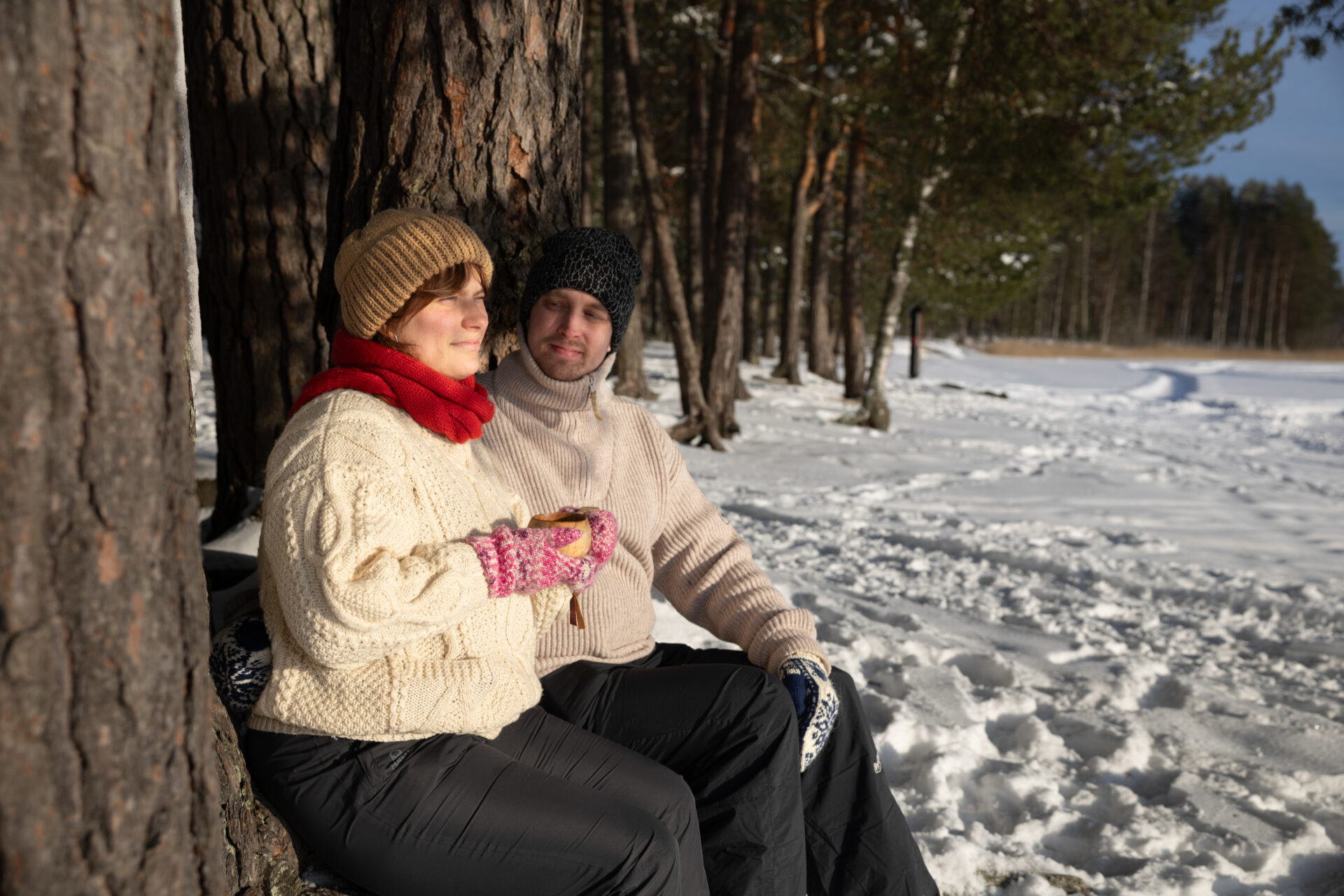 Kaksi henkilö talvella istumassa ulkona ja juomassa kuksasta.