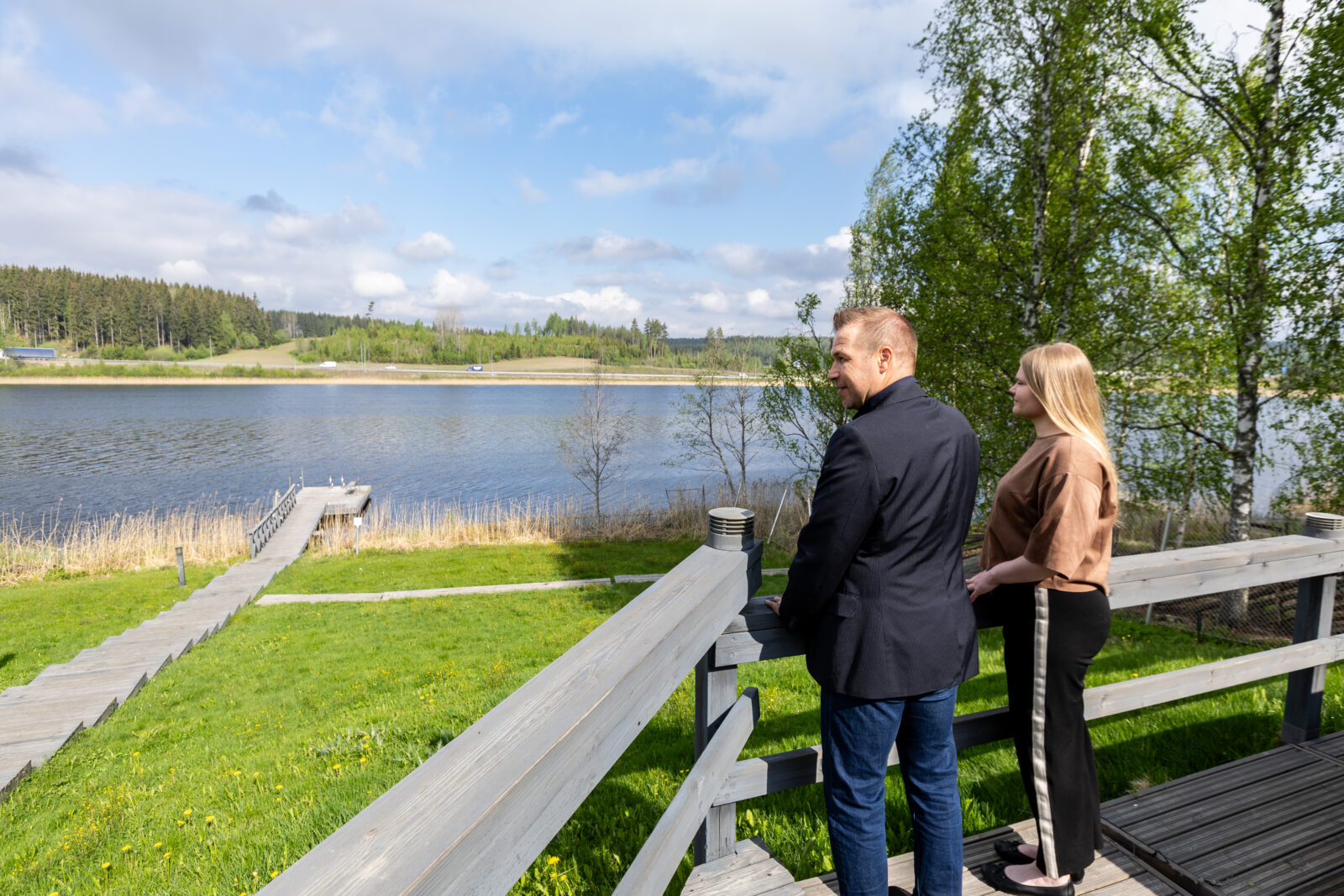 Kaksi ihmistä terassilla katselee järvelle.
