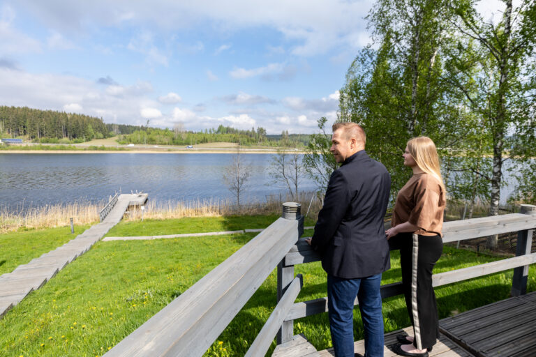 Kaksi ihmistä terassilla katselee järvelle.