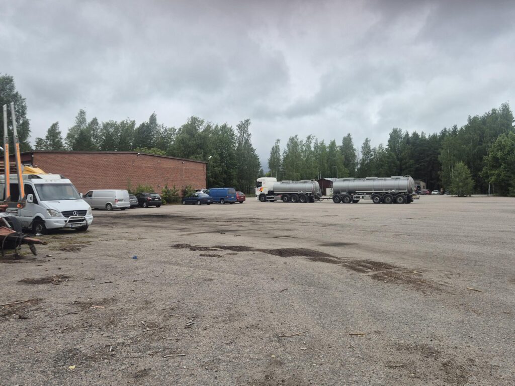 Autoja ja rakennus hiekkapihalla.