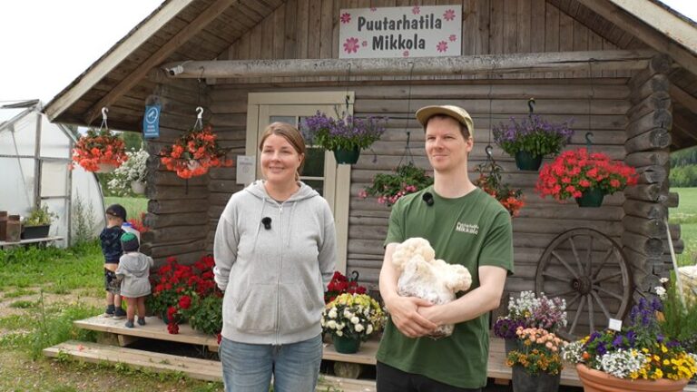 Puutarhatila Mikkolan omistajat seisovat tilan rakennuksen edessä. Oikeanpuoleisella on sieni sylissään.