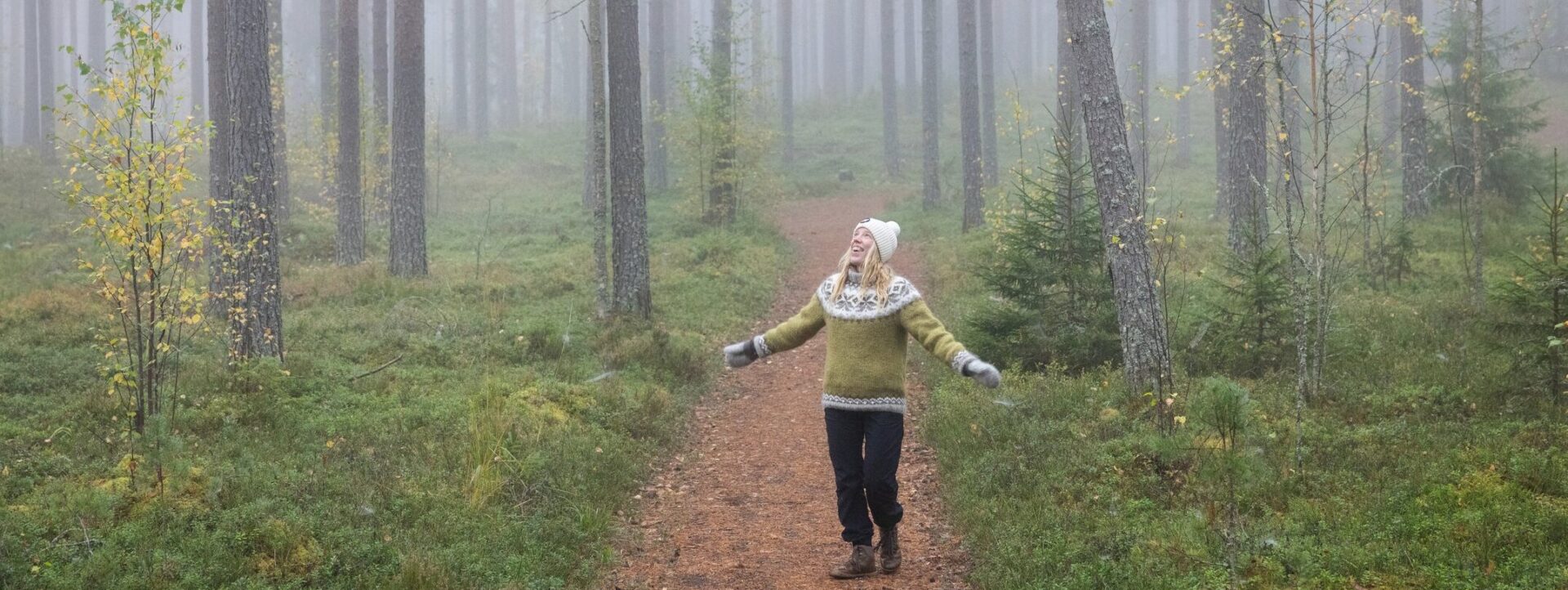 Nainen sumuisessa metsässä.