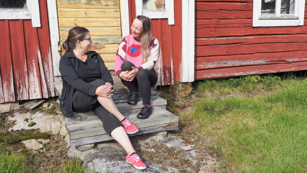 Kaksi ihmistä istuu ulkona vanhan rakennuksen rappusilla.