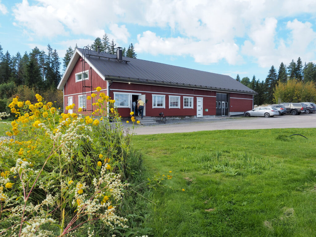 Punainen iso rakennus ulkoapäin, aurinkoinen keli.